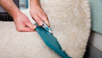 71418294 – close-up of a craftsman hands holding cutter cutting carpet at home